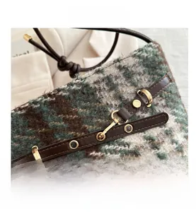 Détail du tissu tweed vert et marron avec boucle en cuir foncé et fermoir doré chic