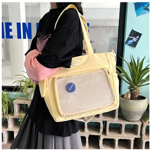 Dettaglio della borsa tote gialla con tasca a rete trasparente e badge con logo moda
