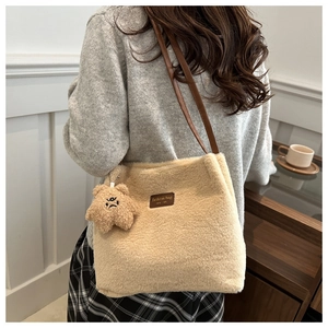 Detail of plush winter tote bag featuring fashion patch and cute bear keychain accessory