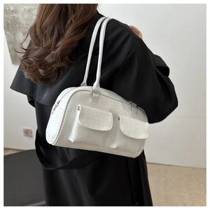 Detailed macro view of white crocodile embossed faux leather shoulder bag on a black coat