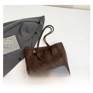 Detailed macro view of dark brown oil wax leather tote bag with braided charm