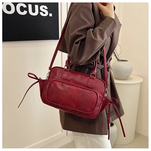 Detail view of burgundy leather backpack with side drawstring bow and vintage glossy finish