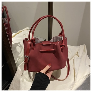 Detail view of burgundy matte bucket bag with knotted handles and adjustable strap