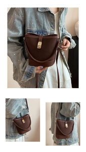 Detail of a dark brown vintage bucket bag with golden hardware and leather strap