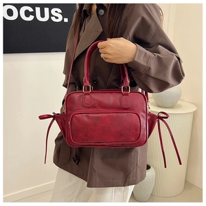 Detail of vintage dark red PU boston bag with side ribbons and front zipper pocket