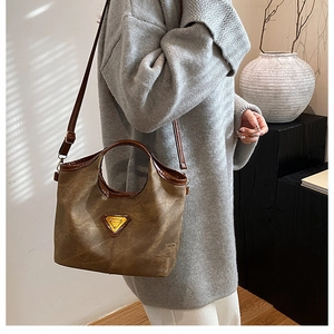 Detail of vintage brown leather tote bag with gold triangle logo and crossbody strap