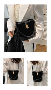 Detail of black bucket bag featuring textured suede panels and gold twist-lock closure