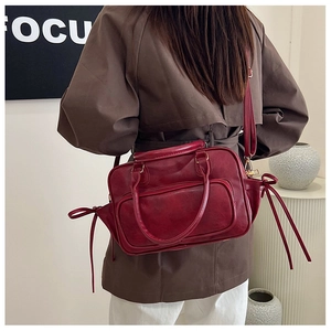 Detail of dark red vintage backpack with front zipper and long decorative straps