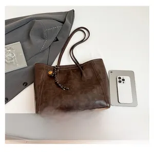 Detail view of large brown vintage leather tote bag with braided knot and iPad for scale