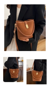 Detail view of retro brown bucket bag featuring gold rotating buckle and premium matte texture