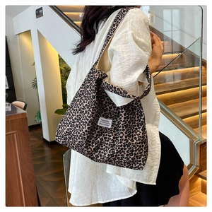 Detailed close-up of a leopard print canvas tote bag featuring a white fashion label
