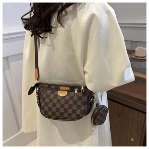 Close-up of brown checkerboard shoulder bag with round pendant and gold hardware
