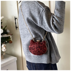 Detail showing red leopard print velvet cat-shaped mini bag with elegant gold chain strap