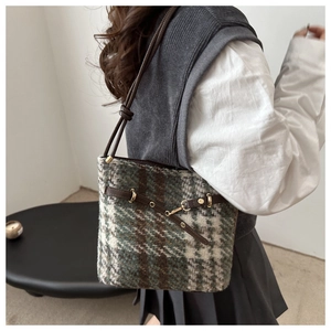 Détail de la texture à carreaux en laine et de la bandoulière en cuir du sac