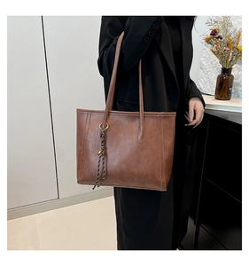 Close-up of a dark brown faux leather tote bag with striped tassel and metal ring detail