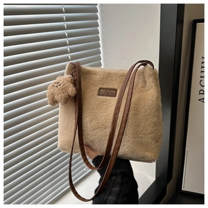 Detailed macro view of soft faux fur shoulder bag with leather strap and cute bear charm
