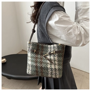 Détail du sac seau rétro en laine à carreaux avec lanières cuir et boucles dorées
