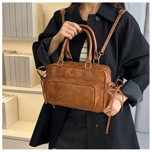 Detail view of retro brown faux leather bag with large front pocket and metal hardware