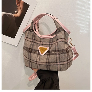 Close-up of pink leather handle and vintage plaid tweed texture with gold logo
