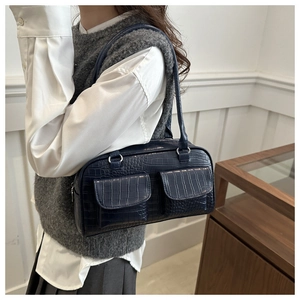 Detail of navy blue croc-effect shoulder bag with silver hardware and front pockets