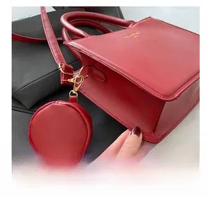 Detail of red leather crossbody bag featuring a golden buckle and small round coin purse