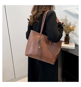 Detail of vintage brown tote bag with leather texture and decorative charm ornament
