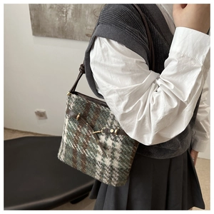 Détail du sac seau en tweed montrant la texture rétro et le mors en métal doré