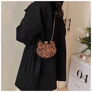 Close-up of a leopard print cat-shaped mini bag with a gold chain strap on a model