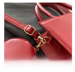 Detail of dark red crossbody bag showing golden adjustable buckle and removable pouch