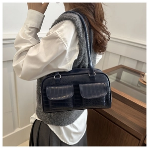 Detail of navy blue croc-embossed shoulder bag featuring two front flap pockets