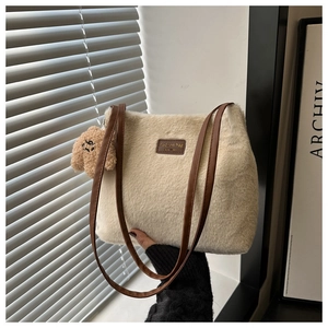 Close-up of white plush shoulder bag with brown leather strap and cute bear charm