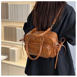 Detailed view of caramel brown vintage backpack with ribbon side ties and gold zippers