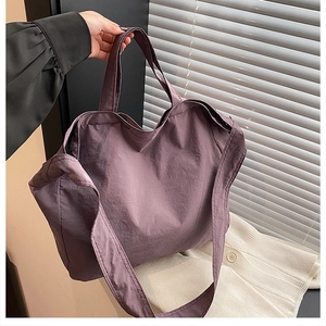 Dettaglio macro della borsa tote in tela viola scuro con manici e tracolla regolabile