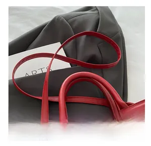 Detail of red leather handbag with gold embossed logo and elegant rounded handle
