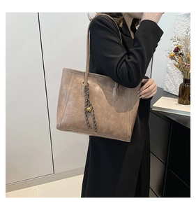 Detail of vintage khaki tote bag with golden bell charm and elegant knot accessory