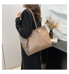 Detail of the vintage textured brown leather tote bag with elegant decorative tassel
