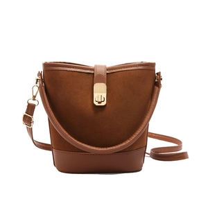 Minimalist brown bucket bag in textured faux suede and leather with gold buckle detail