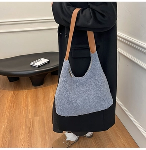 Blue fleece tote bag with brown leather handles shown carried by a model in a modern interior