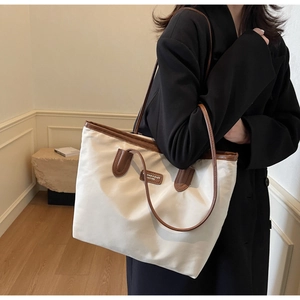Detail of minimalist cream tote bag with brown leather trim and large capacity interior