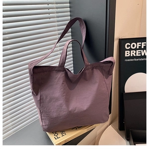 Dettaglio di una grande borsa tote in nylon viola con doppi manici e trama morbida e stropicciata