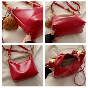 Detail view of red glossy leather hobo bag with teddy charm and gold hardware