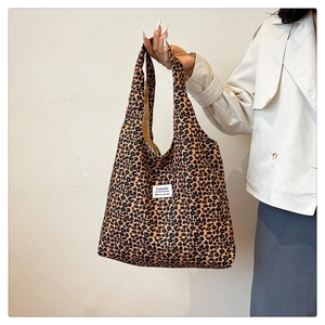 Close-up of leopard print tote bag with white fashion label and wide shoulder strap