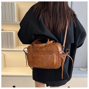 Detail showing vintage brown faux leather Boston bag with side tassels and long strap