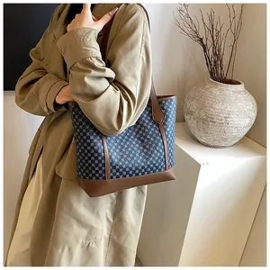 Retro tote bag with blue geometric pattern and brown leather straps worn by model