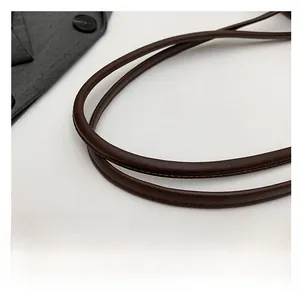 Detail of deep brown leather tubular shoulder strap with fine stitching and soft texture