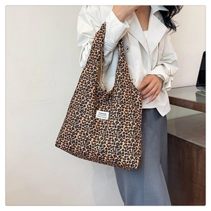 Detailed close-up of leopard print fabric tote bag with fashion label on white coat
