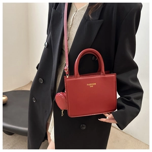 Detail of red square shoulder bag with heart pendant and golden fashion text