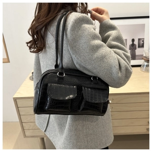 Close-up of black crocodile pattern tote bag with front pockets on a model shoulder