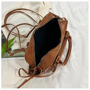 Macro view of retro brown PU leather handbag showing three zippered storage compartments