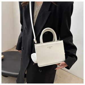 Close-up of a white minimalist crossbody bag with round coin purse and gold fashion text